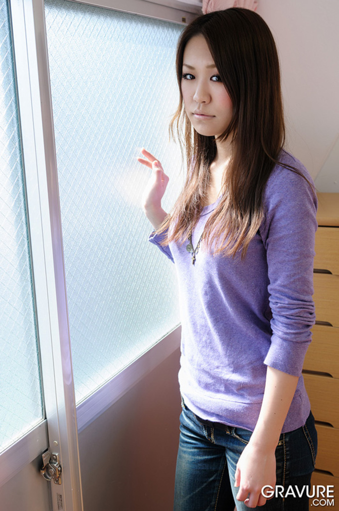 Standing by window long hair purple sweater wearing jeans