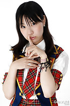 Momoko Miura finger raised to lips long hair down over her shoulders wearing white whirt plaid tie and skirt