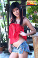 Long hair over her bare shoulders raising red top over her waist denim shorts undone