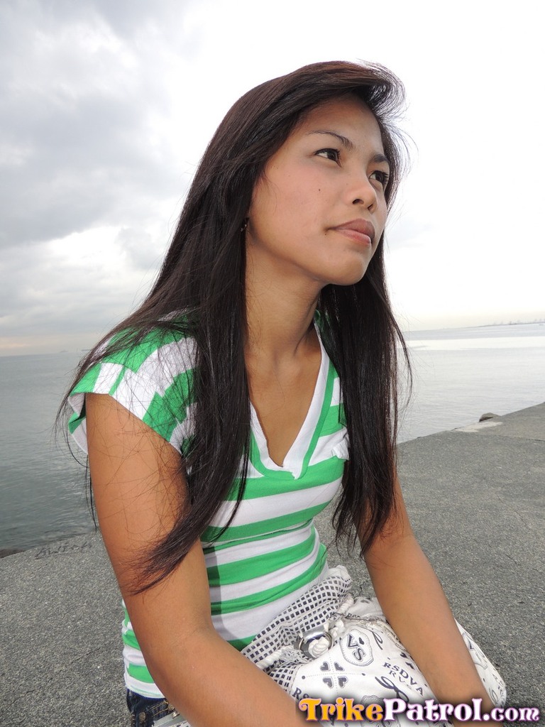 Seated on harbour wall long hair blowing in the breeze wearing striped top
