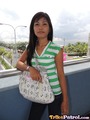 Overlooking busy road long hair over her shoulder wearing green striped top carrying bag