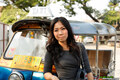 Standing beside tuk tuk handbag over her shoulder long hair